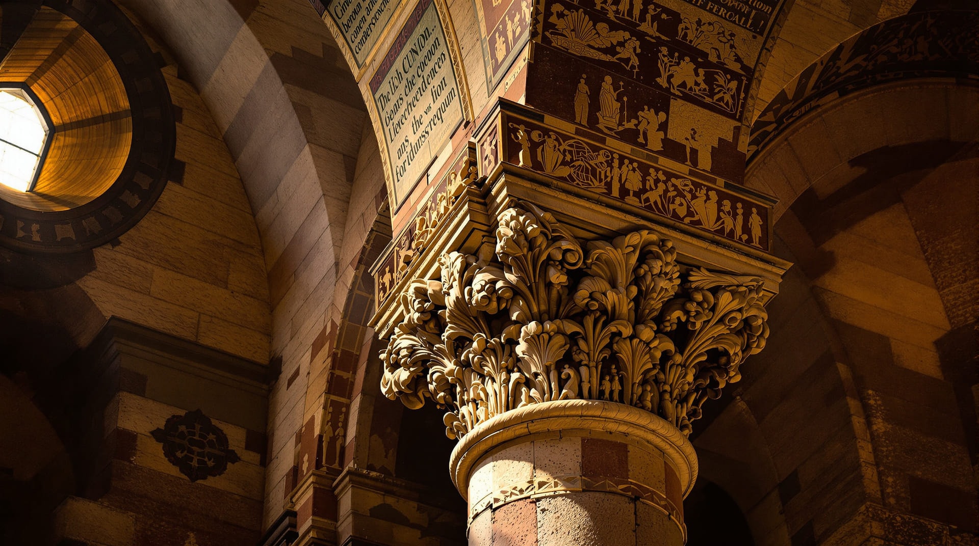 Carved stone capital and arch springing lit by a shaft of daylight inside a dim basilica